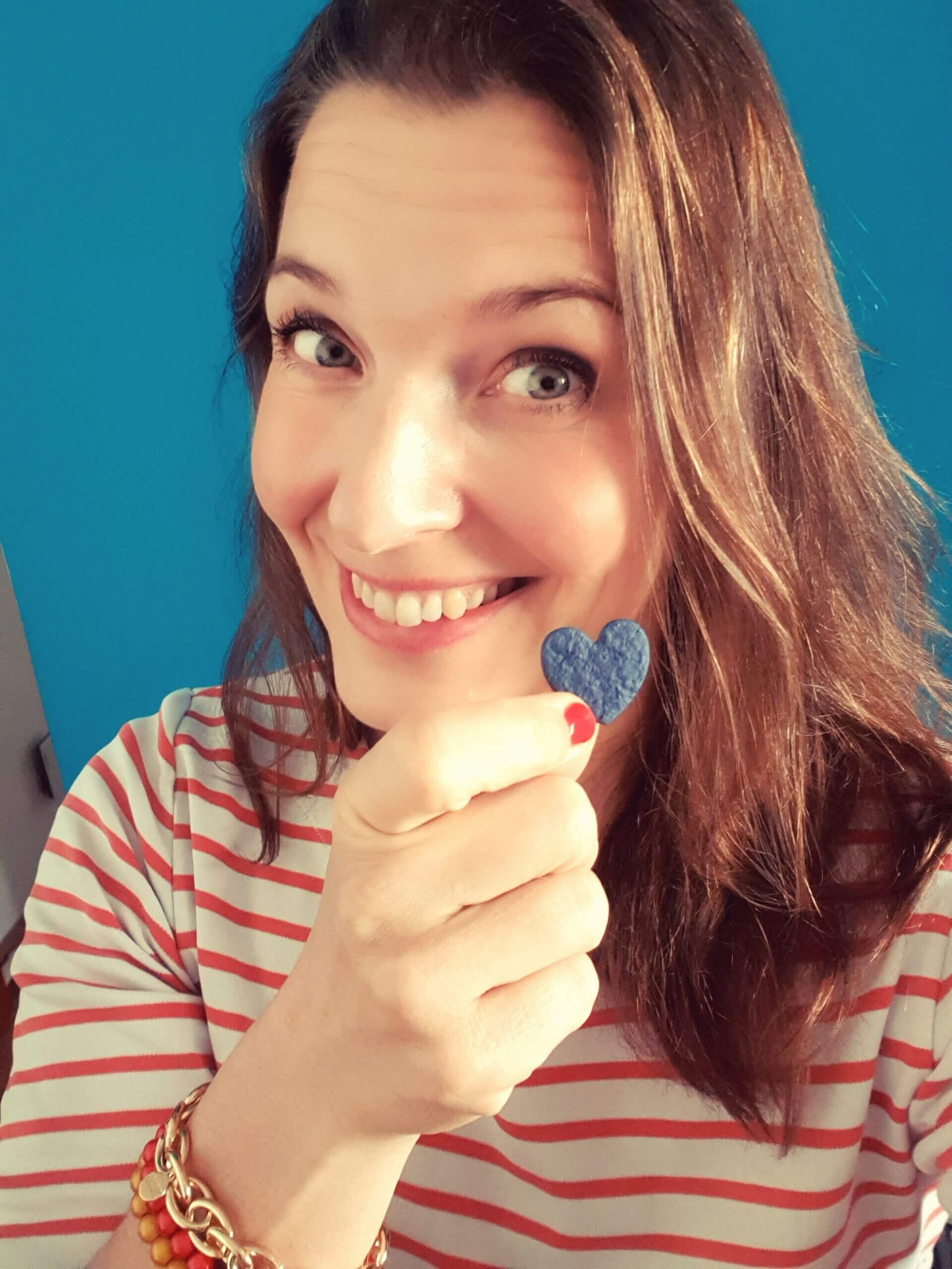 Porträt von Kristin Schombel mit einem kleinen Herzsymbol in der Hand
