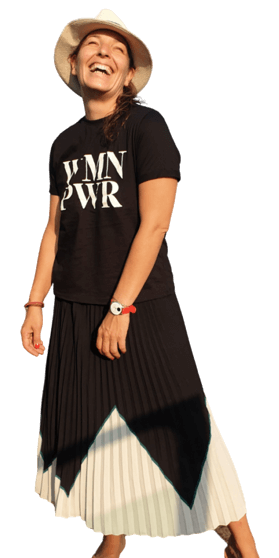 Kristin Schombel – Marketing- und Eventexpertin Ganzkörperaufnahme von Kristin Schombel mit Hut, schwarzem Shirt und plissiertem Rock in Schwarz-Weiß